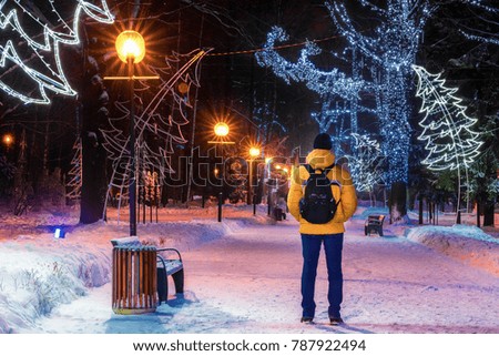 Winter Park in Khimki, Moscow region, Russia. A man admires the night of the Christmas lighting of the Park.