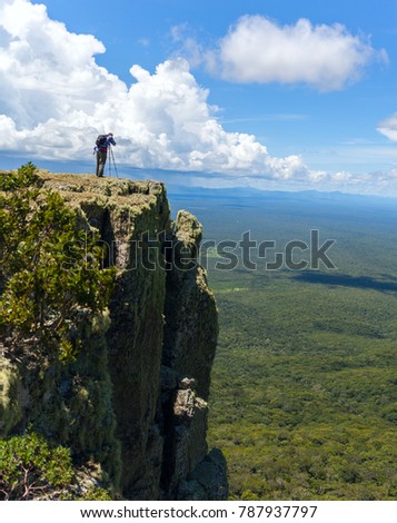 Wildlife photographer on mountain summit taking pictures of sunset in landscape and blue sky. Amazon rain forest n the border of Bolivia and Paraguay