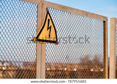 warning danger of electricity sign on a metal fence outside on an old fence
