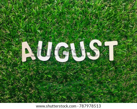 Image August,wooden alphabet August on green grass background with copy space for your text. Concept be used for calendar, month and background. Blur picture and exposure. Vintage style.