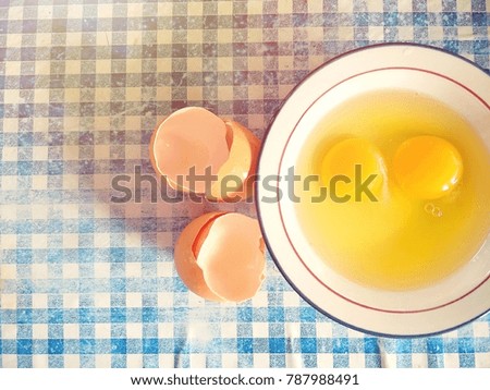 Fresh raw eggs in a bowl at right image with morning sunshine on old blue and white square pattern floor