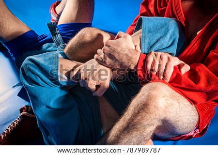 Close-up two wrestlers of grappling and jiu jitsu in a blue and red kimono makes armlock. Wrestler submission wrestling  blue tatami