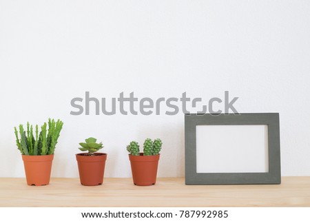 Succulent plant in pot and frame photo on table