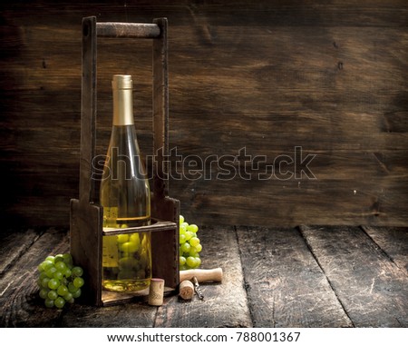 Wine background. White wine on a stand with branches of fresh grapes. On a wooden background.