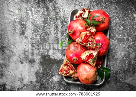 Ripe pomegranates on steel tray. On a rustic background.
