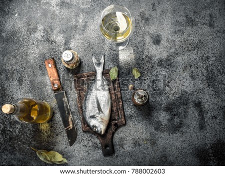 Fresh unprepared Dorado fish with white wine. On a rustic background.