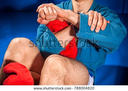 Man wrestlers of grappling and jiu jitsu in a blue and red kimono makes submission wrestling. Fighting techniques:   armbar, armlock Royalty-Free Stock Photo #788004820