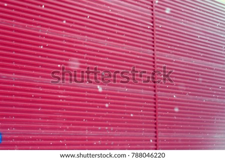 Colorful red wall and falling white snow, snowflakes. Winter holiday background