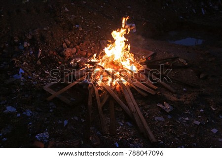 A small fire with dry sticks and twigs burn  on the rubbish dump area. (low light high Iso)