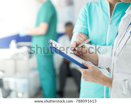 Medical staff working at the hospital: doctor and nurse checking a patient's medical record on a clipboard, healthcare and medical exams concept