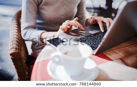 Young businesswoman sitting in a cafe drinking coffee and working with laptop, close-up photo. Business, education, lifestyle concept