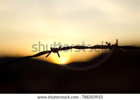 Sunset behind barbed wire, military space.