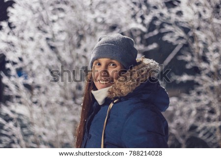 Smiling girl at night on a background of snow-covered trees in winter
