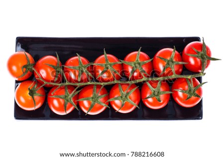 Branch of ripe cherry tomatoes on plate, top view. Studio Photo