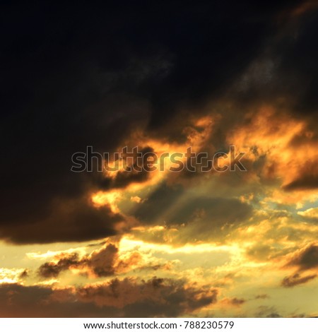 Dramatic cloudy evening sky with rays of sunshine penetrating the clouds and creating tense athmosphere with vivid bright colors, square shaped picture.