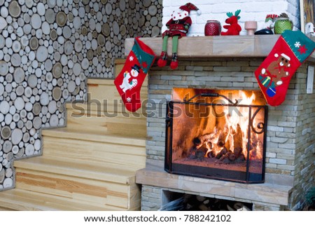 Fireplace with Christmas decorations. The firewood is burning in the fireplace.