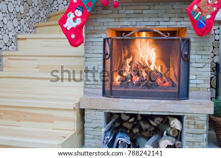 Fireplace with Christmas decorations. The firewood is burning in the fireplace.