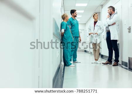 Group of medical staff discussing in clinic hallway. Healthcare professionals having discussion in hospital corridor. Royalty-Free Stock Photo #788251771