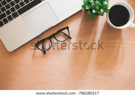 Coffee, computer, eyeglasses  and tree pot on brown wooden desk in office, Workspace.