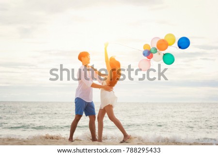 Romantic couple relaxing on the beach and enjoying beautiful sea view with colored balloons