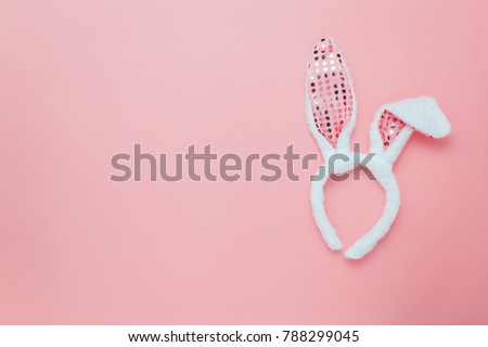 Top view aerial image of decoration & symbol Happy Easter holiday background concept.Flat lay accessory costume bunny ear on modern beautiful pink paper at home office desk.Free space for design.