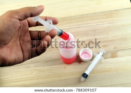 Man hand using syringe to draw sucking red medicine from bottle. Preaparing for medication. Medical concept