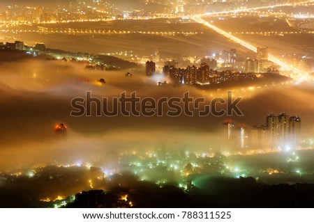 Aerial view of Taipei on a foggy evening, the vibrant capital city of Taiwan, with colorful lights of buildings & streets glistening in the mist ~Scenery Taipei City in dense fog & ethereal atmosphere