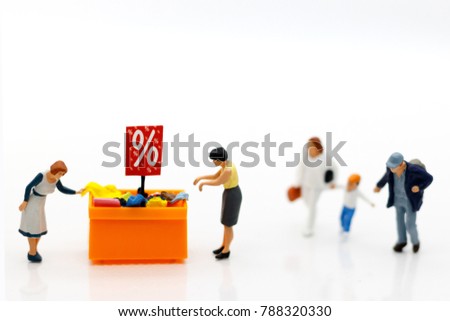 Miniature people: Shoppers buy goods on sale with discount tray.