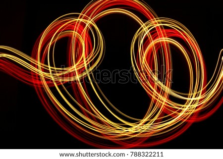 Red and gold light painting photography, swirls and loops of fairy lights, long exposure photo, against a black background