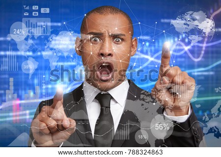 World economics and business concept. Shocked terrified clever businessman touches virtual screen, has horrified look as realizes falling sales, analyzes diagrams or charts, checks stock market