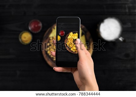 Hand's of woman taking picture photo food with mobile smart phone. Top view. Mexican nachos with two kind sauce on photo