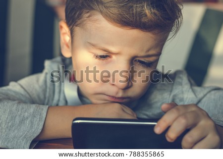 Little boy using mobile phone and watching something on the internet. 