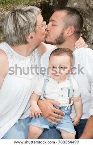 happy mother and father kissing with little son in park