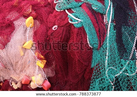 Macro view of colored fishing nets. Green red and white are the main colors of this textured picture. An abstract image composed with a traditional fishing equipment. Pattern composed of three nets.