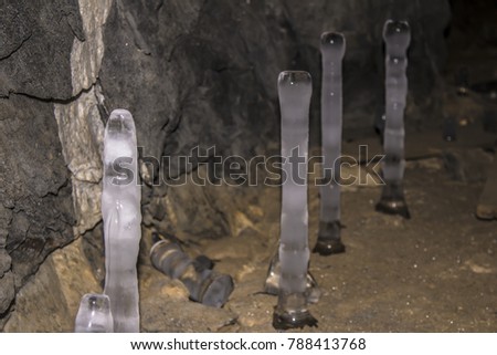 vertical stalactites grow on rocks in a cave