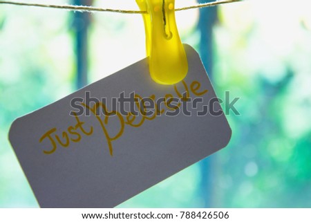 "Just believe" card hanging on the wire,  background - light behind the bars. Concept - always believe, even when the way is with obstacles, there is always the light