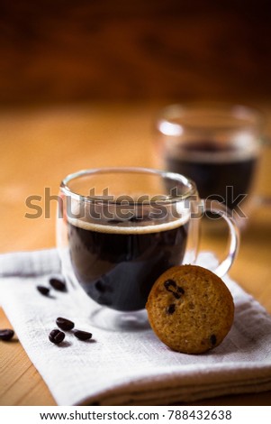 Two cups of espresso coffee on brown napkin in bodum double bottom glasses with butter cookie on wooden background