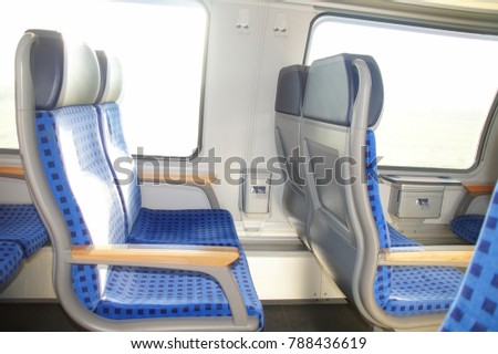 Inside the train carriage, Germany. Empty train seats next to the window with a small table and a garbage container. Translation of the sign: A large waste container is in the anteroom