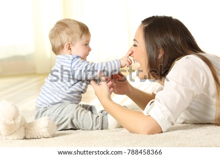 Happy baby touching his mother face lying on a carpet at home Royalty-Free Stock Photo #788458366