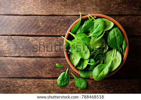 Fresh spinach leaves in bowl on rustic wooden table. Top view. Royalty-Free Stock Photo #788468518