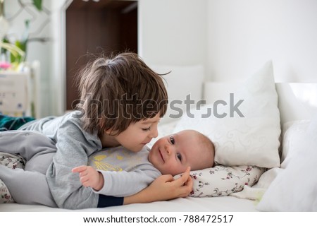 Two children, baby and his older brother in bed in the morning, playing together, laughing and having a good time, sharing special moment, bonding Royalty-Free Stock Photo #788472517