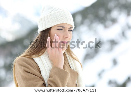 Angry woman using a sking protection moisturizer cream in winter in a snowy mountain Royalty-Free Stock Photo #788479111