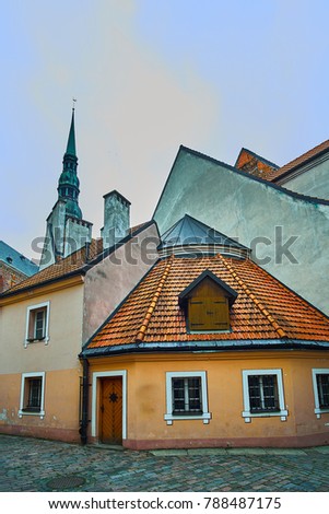 Old medieval evening narrow street with Saint Peters Lutheran church on the background in Riga Latvia. Retro styled.