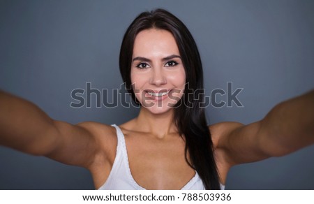 Funny picture. Beautiful smiling young woman photographes herself on the phone or doing selfie on a gray background isolated. concept 