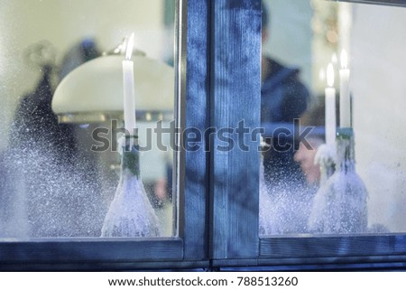 Frosted window with burning candles on the windowsill