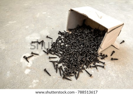 Close-up image of many small black screws on concrete background