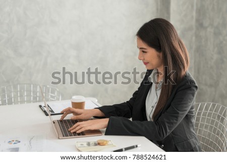 Beautiful asian young businesswoman working on laptop in her workstation