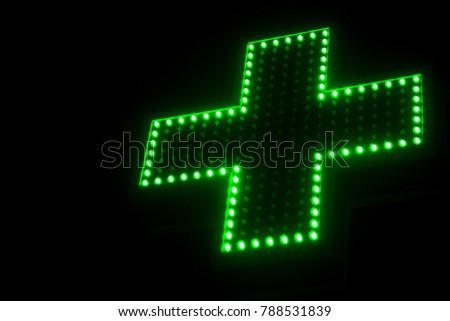 Neon light bulbs green cross sign of pharmacy   or Drug store symbol. Isolated on black night background 