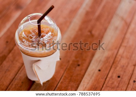 Landscape object picture:Cold Coffee in a plastic glass placed on a wooden table.