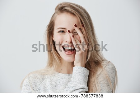 Headshot of cute woman with dark eyes, blonde long hair, happy gentle smile rejoicing her success. Cheerful woman having birthday having pleased expression and pleasure. Face expressions Royalty-Free Stock Photo #788577838
